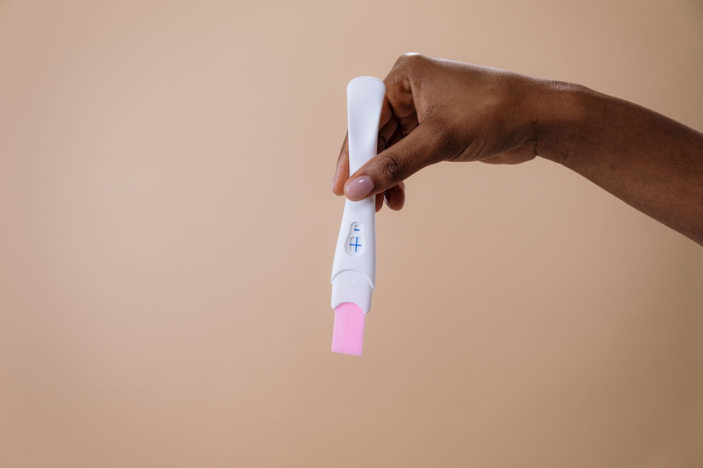 A hand holding a pregnancy test